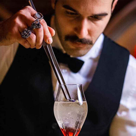 male inserting garnish in cocktail using straight tip tweezer