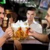 Two guys cheers with a crocodile ice piece inside their glass