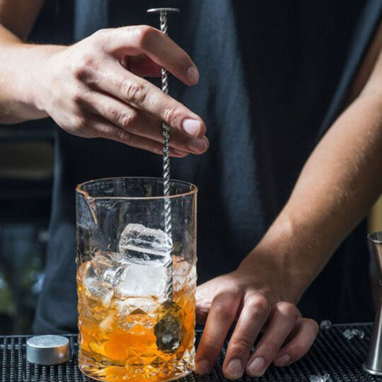 Bartender mixing an alcoholic drink in a glass using the disk tail spoon
