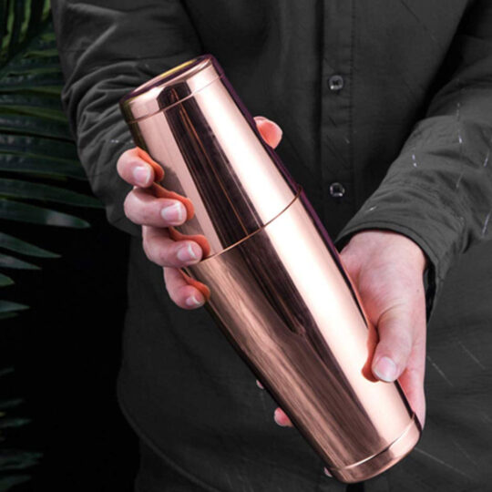 Copper plated stainless steel Boston cocktail shaker held in someone's hands