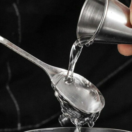 Alcohol being poured from a jigger onto the forky spoon