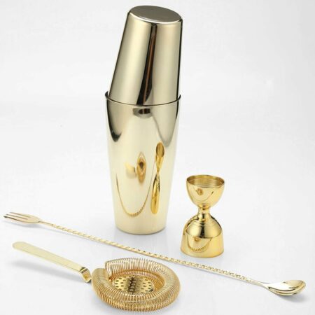 Four piece gold plated stainless steel cocktail bartending set of a Boston Shaker and a Hawthorne Strainer and a Bar Spoon and a Jigger