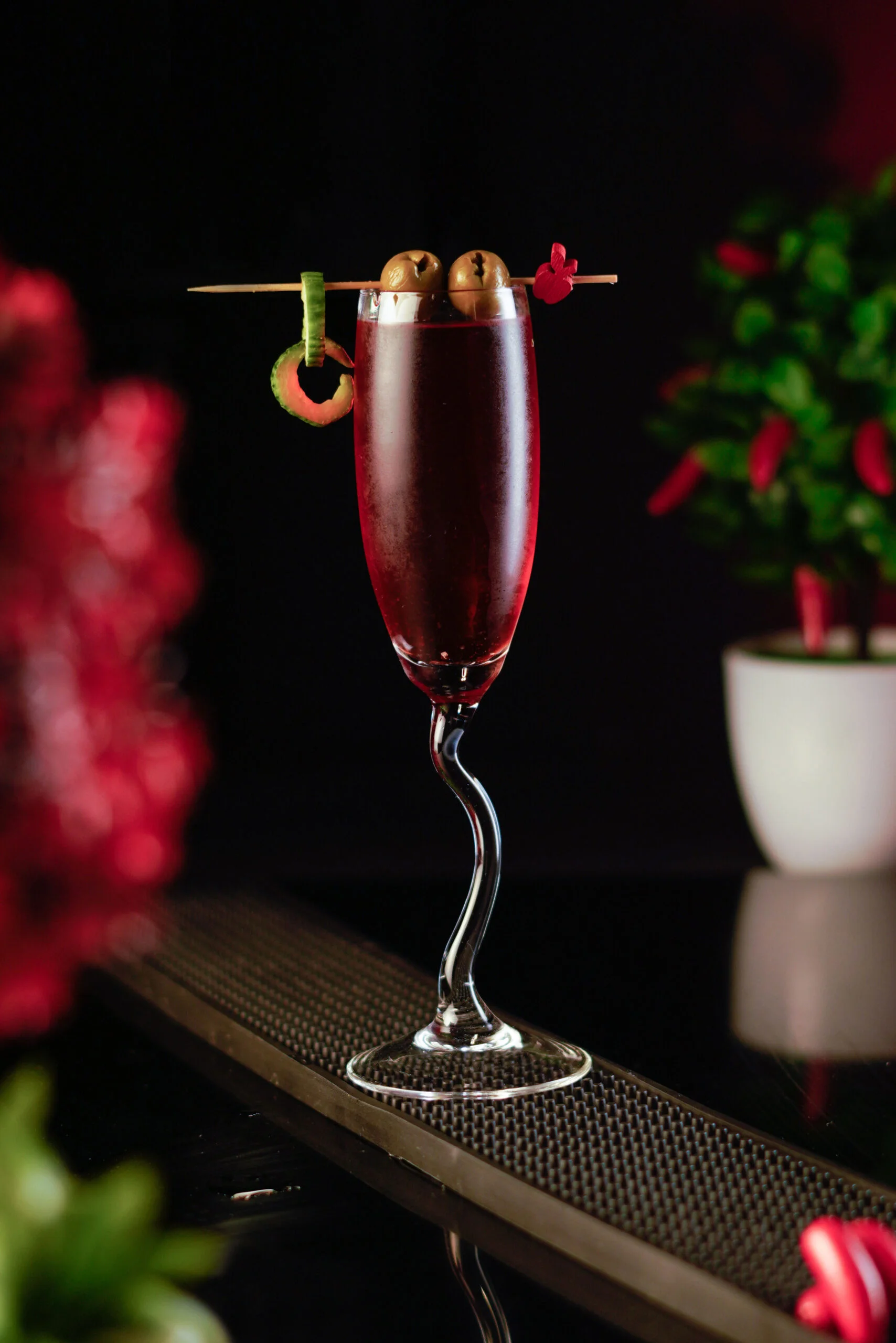 The Deviated Flute Glass Laying on the long rectangular rubber bar mat around a dark and red background