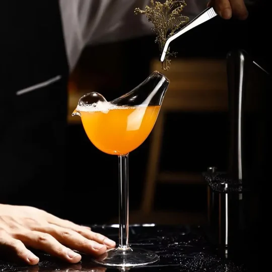 Wingless Bird Cocktail Glass with garnish being placed, perfect for artistic and elegant presentations.