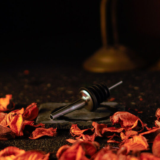 Stainless Steel Pourer on a stone bar mat with roses around it