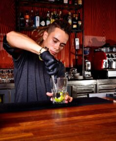 Bartender Muddling Lemons Inside Mixing Glass Using Muddler