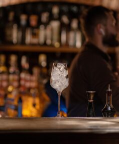 Bartender listening to music inside a bar with a glass filled with ice on the counter