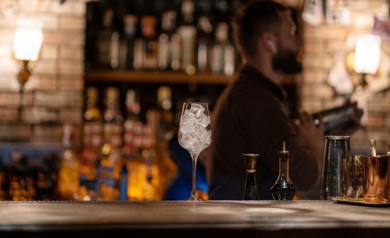 Bartender listening to music inside a bar with a glass filled with ice on the counter