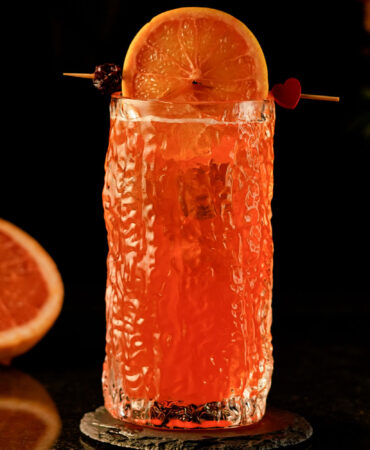 Orange cocktail inside a carved highball glass with a texture