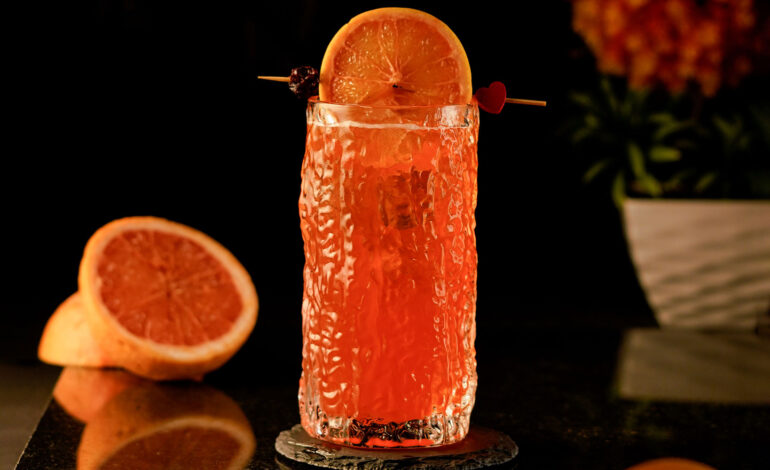 Orange cocktail inside a carved highball glass with a texture