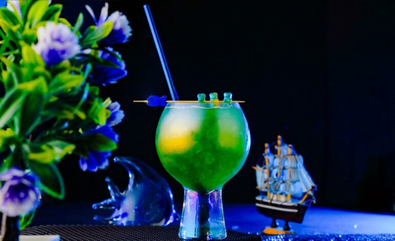 Green looking cocktail inside an exquisite glass around a blue lighted background