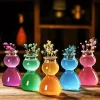 A collection of five round-bottomed shot glasses, each containing a different colored liquid and topped with small bunches of flowers.