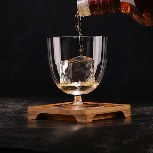 Liquor being poured inside a cocktail glass with a small stem and a large body