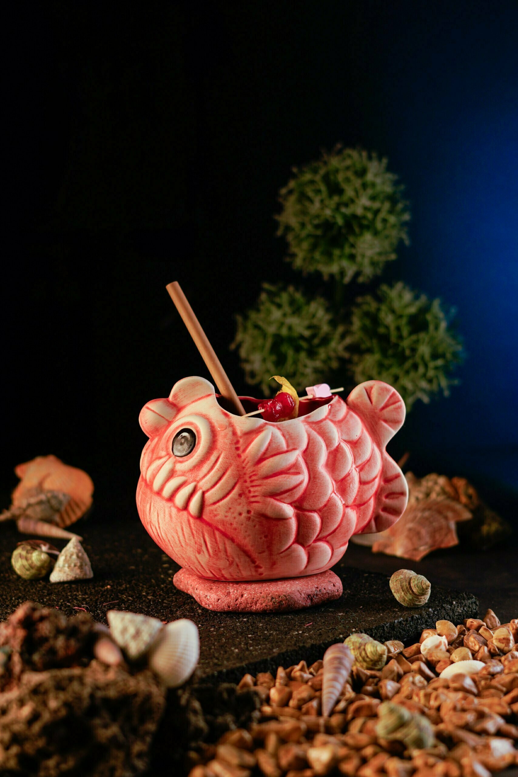 Pink Piranha cocktail tiki Mug with shells around it