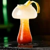 Mushroom-shaped glass with red-orange cocktail and citrus garnish, perfect for creative drink presentations.