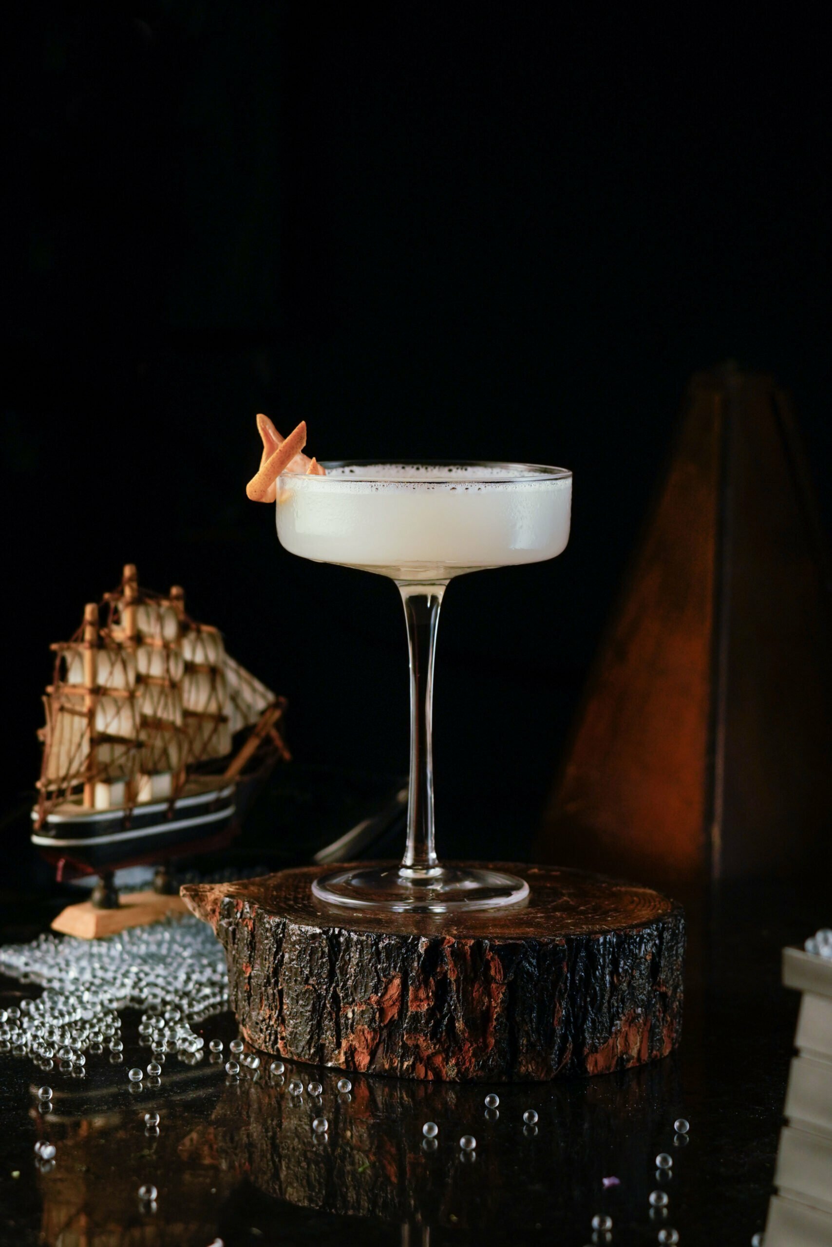 White cocktail inside a circle coupe glass garnished with an orange peel