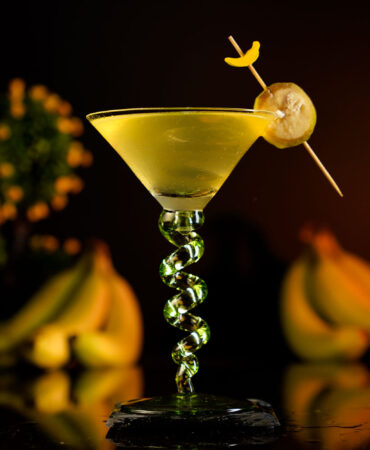 Yellow Cocktail in a beautiful martini glass around bananas