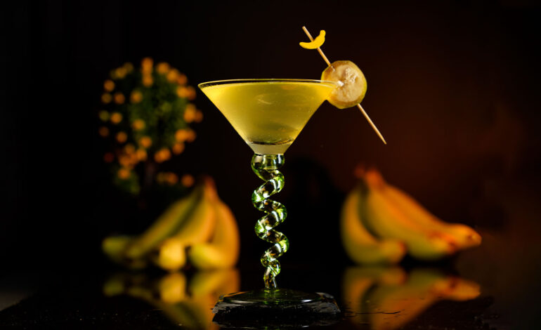 Yellow Cocktail in a beautiful martini glass around bananas