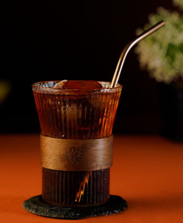 Dark coffee cocktail inside a striped tumbler glass