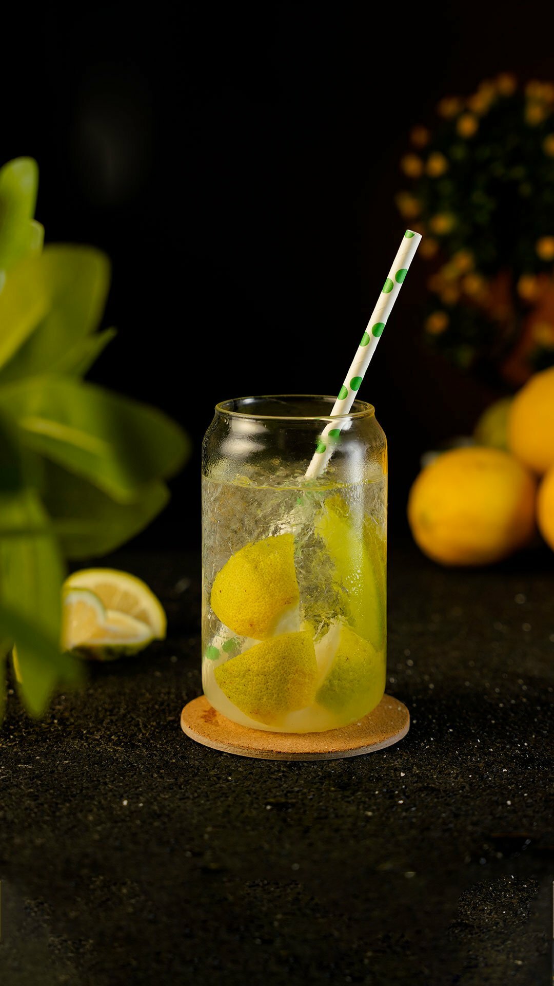 Cocktail with lemon slices filled inside a glass can with lemons and leaves around the background