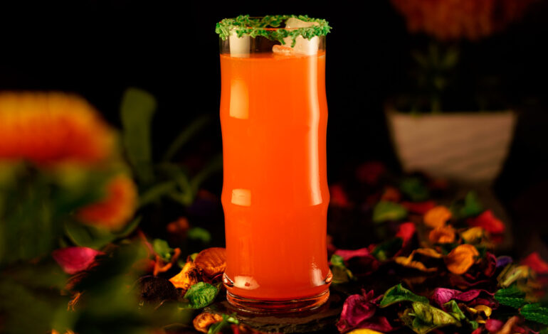 Orange exotic cocktail in an edged collins glass garnished with green sprinkles