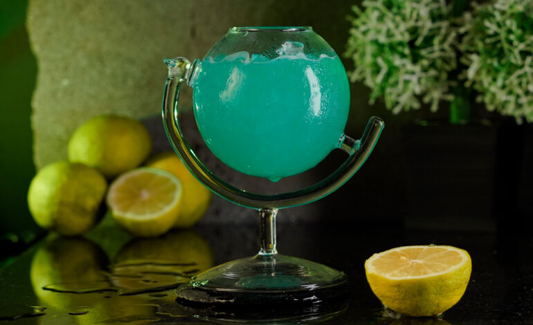 Blue cocktail inside a globe cocktail glass