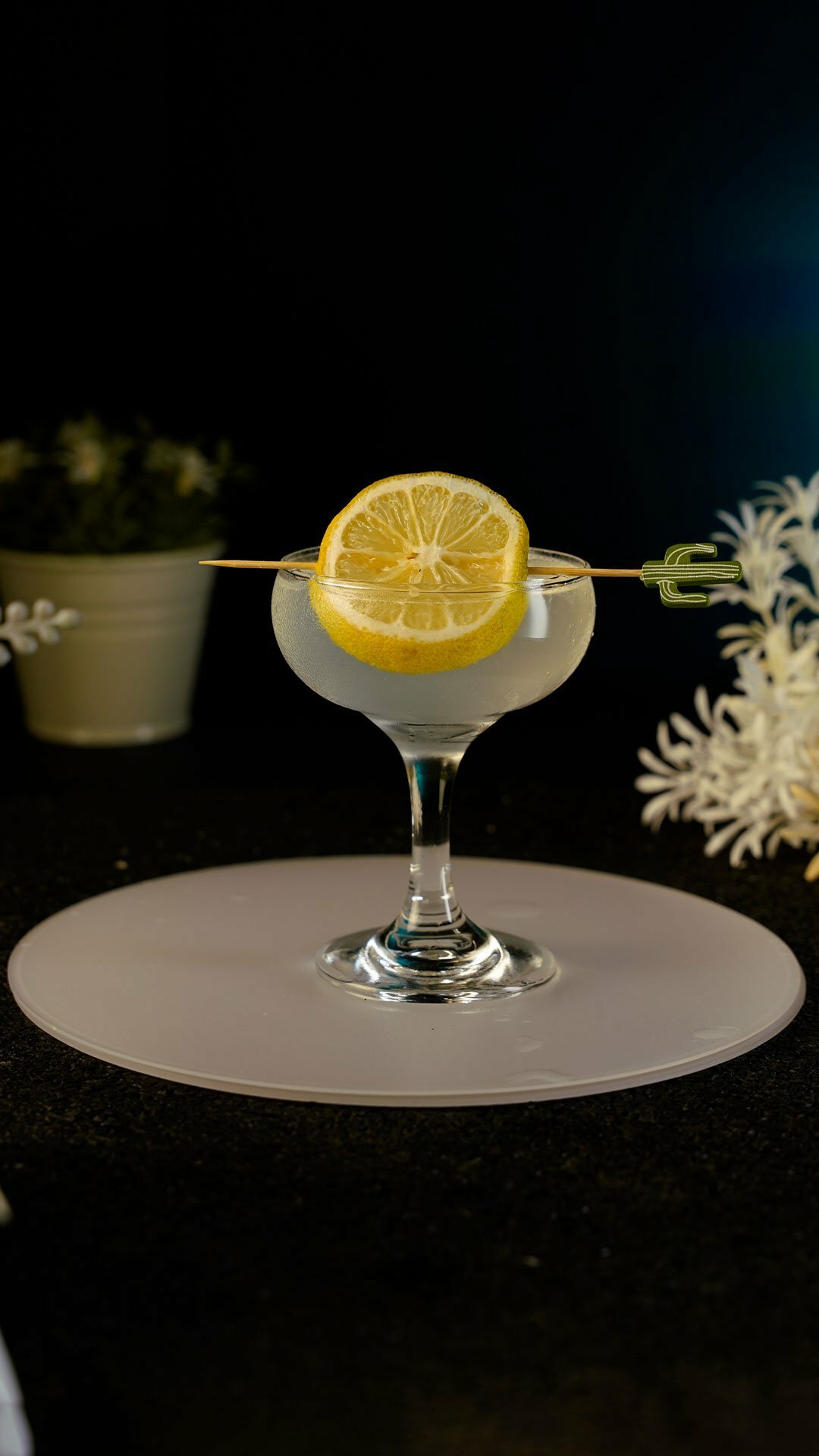 Gin cocktail served in a small coupe glass garnished with a lemon wheel on a cocktail pick