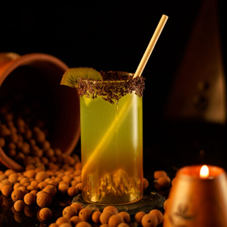 Highball Glass with a mountain design filled with a kiwi cocktail around a chocolate background