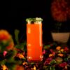 Collins glass filled with orange cocktail around a colorful background