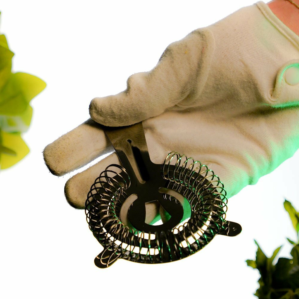 Bartending Accessory Called a Hawthorne Strainer held inside a hand wearing white gloves