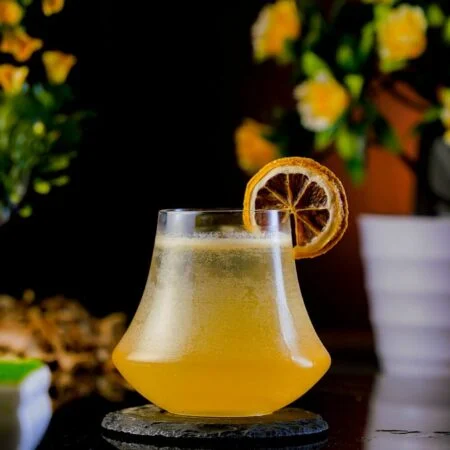 Orange Cocktail inside a short glass garnished with a dried orange wheel