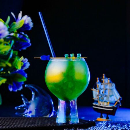 The Lagoon Cocktail inside a skol cocktail glass around a blue background