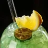 Close-up view of ‘The Double Bubble’ stemware showcasing the top section filled with ice and garnished with a slice of orange and a smaller citrus slice, set against a dark background.