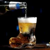 Golden beer being poured into a clear cowboy boot-shaped glass, showcasing its unique design and effervescent contents against a dark backdrop.