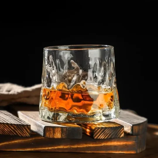 Crescendo whisky glass from the Sip & Swirl Collection, featuring elegant horizontal ridges and a unique rotating base, filled with amber whisky.