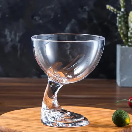 Clear glass with a unique twisted stem design, placed on a wooden surface, perfect for cocktails and elegant bar settings.