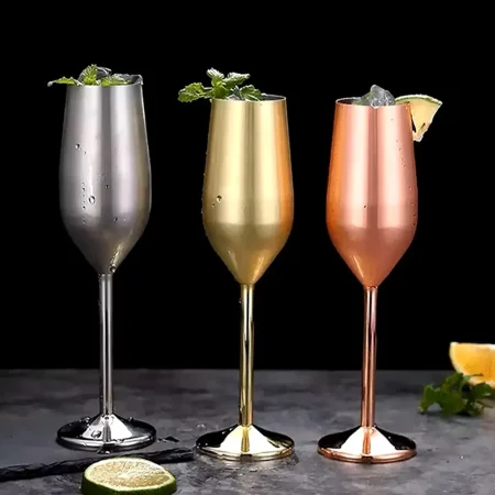 A set of three stainless steel champagne glasses in silver, gold, and copper finishes, each holding 200 ml and adorned with a sprig of mint.