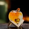 Spherical 480 ml cocktail glass with orange-yellow gradient drink, flower garnish, and wooden stand