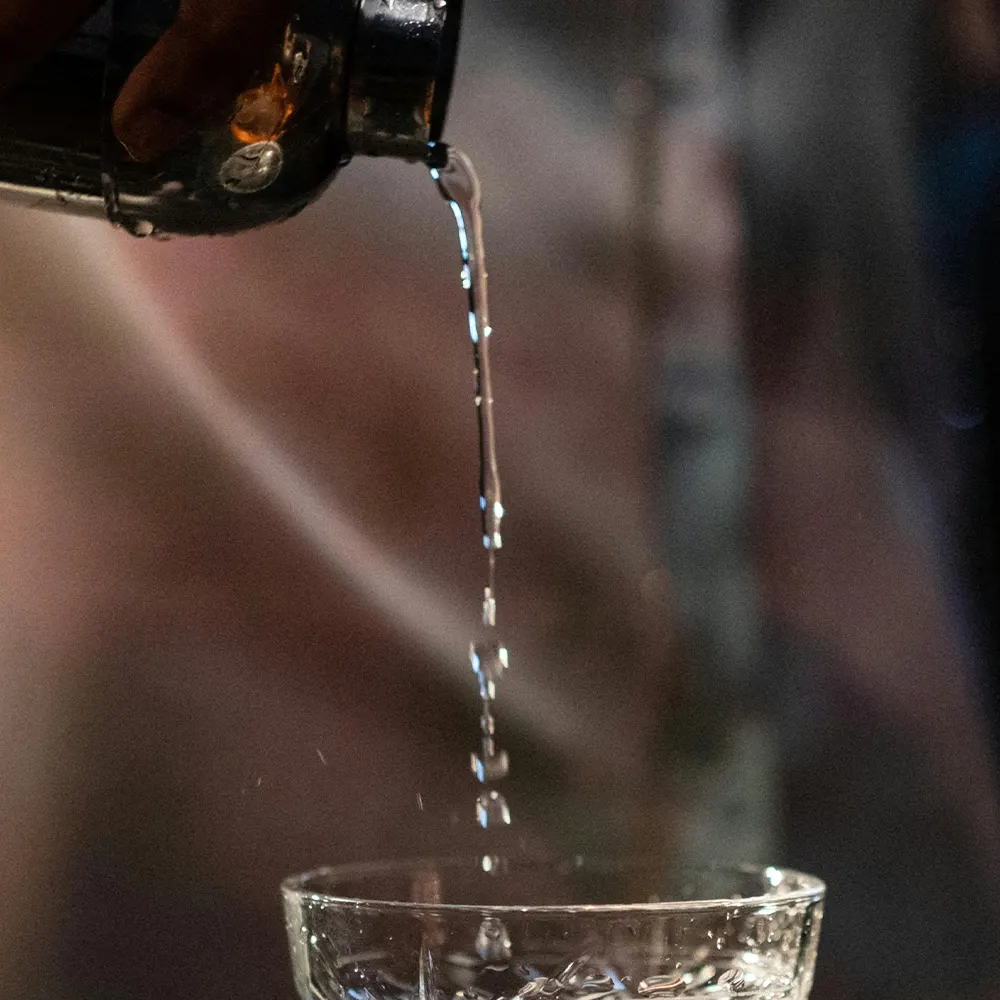 Close-up of a hot beverage being poured into a transparent mug, highlighting the warmth and comfort of enjoying hot cocktails.