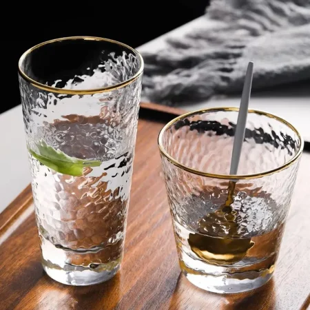 Elegant Golden Cascade Tumbler set featuring a hammered glass texture and luxurious gold rim. The image displays the short 10 oz variant alongside the taller 11 oz version, both ideal for serving sophisticated cocktails