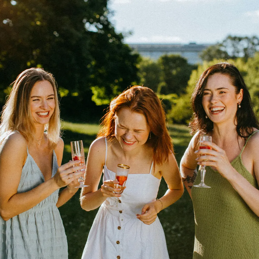 Three individuals celebrating outdoors with glasses in hand, highlighting the joy and assurance of premium drinkware backed by a satisfaction guarantee.