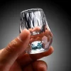 a hand holding a luxurious turquoise gemstone shot glass. The glass features a hand-blown faceted design with a vibrant turquoise-infused base, showcasing its 0.5 oz capacity. This elegant piece is part of an exclusive luxury drinkware collection, highlighting high-quality craftsmanship and unique style.