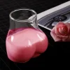 Novelty ‘La Derrière’ glass designed to resemble human buttocks, holding 15 oz of pink beverage, placed beside a pink rose on a patterned black surface – perfect for fun drinkware and cocktail enthusiasts.