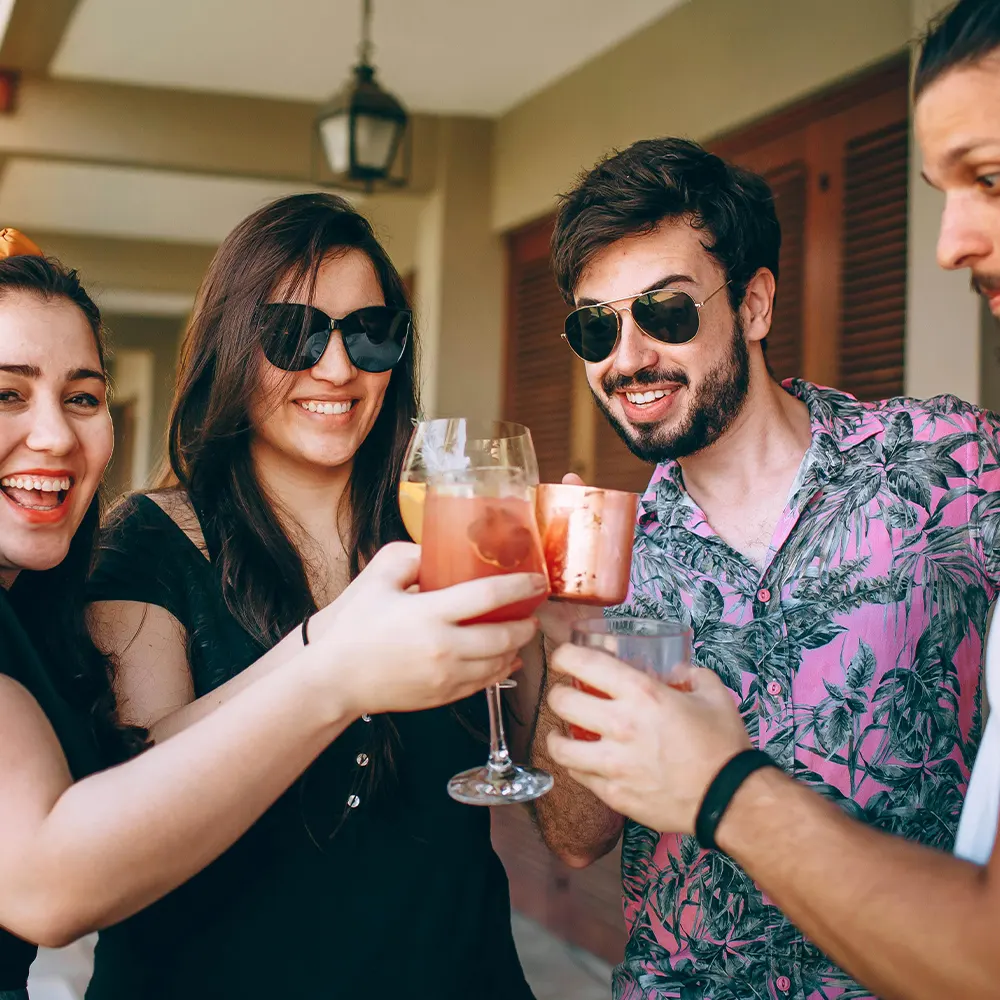 Three individuals holding glasses with beverages at a social gathering, highlighting the stylish and versatile design of premium drinkware that adds flair to any event, from casual brunches to elegant soirées.”