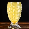 Textured Mermaid’s Embrace glass filled with yellow beverage, placed on a wooden surface against a dark background