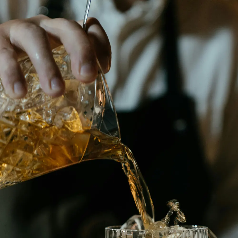 A close-up of a liquid being poured from one container into another, capturing the dynamic splash and highlighting the versatility and elegant design of premium drinkware for whisky, cocktails, and more