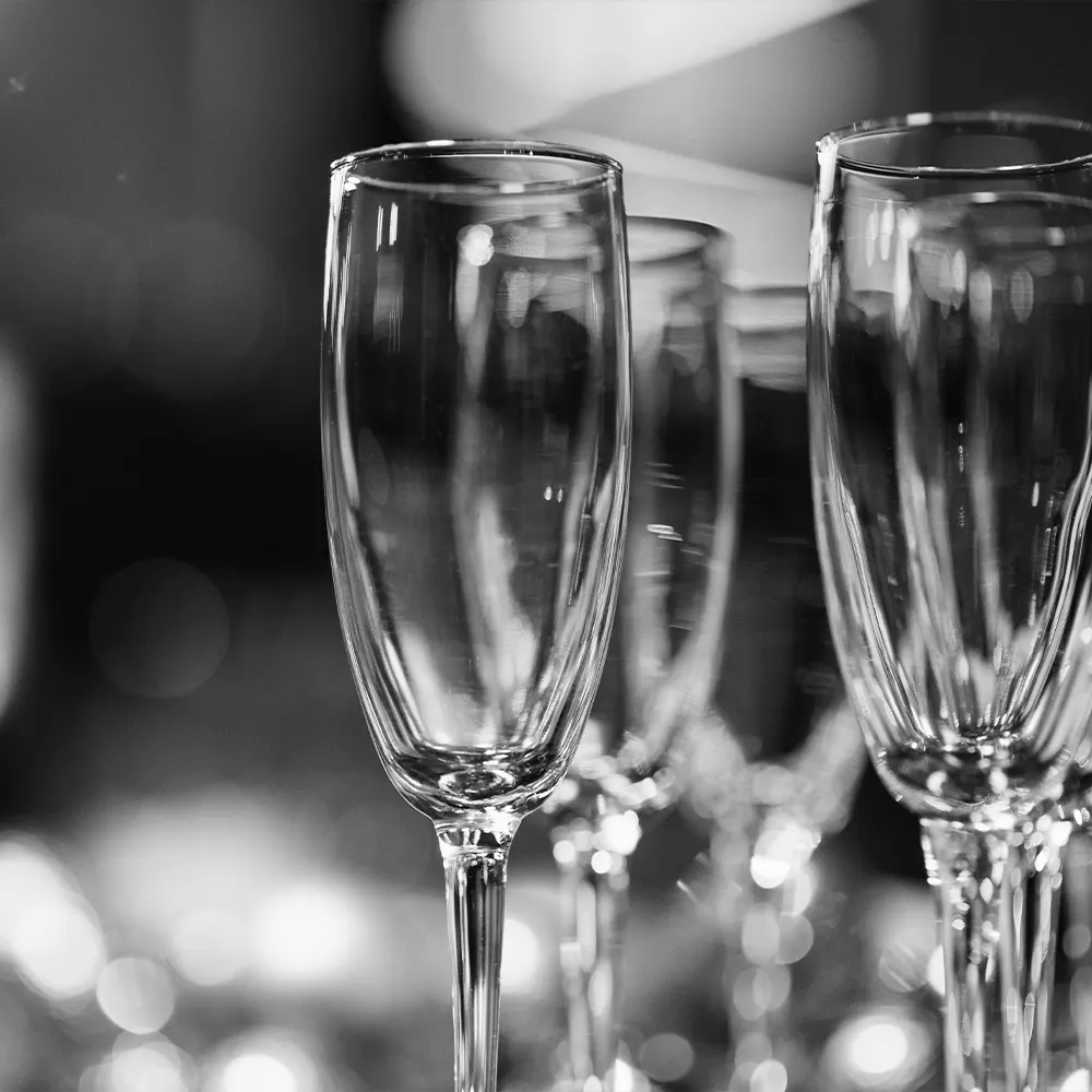 Close-up of several clear glass champagne flutes, highlighting practicality and ease of cleaning as dishwasher-safe drinkware.