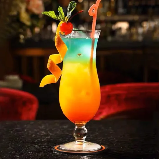 420 ml Tempest Twist Glass filled with a colorful layered cocktail, garnished with orange peel, cherry, and mint, with a pink straw.