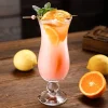 420 ml Tempest Twist Glass filled with a pink cocktail, garnished with orange and mint, on a wooden surface with lemons and oranges in the background.