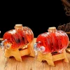 Two glass beverage dispensers with embossed pineapple designs, filled with reddish-orange liquid, on wooden stands with metallic spigots.